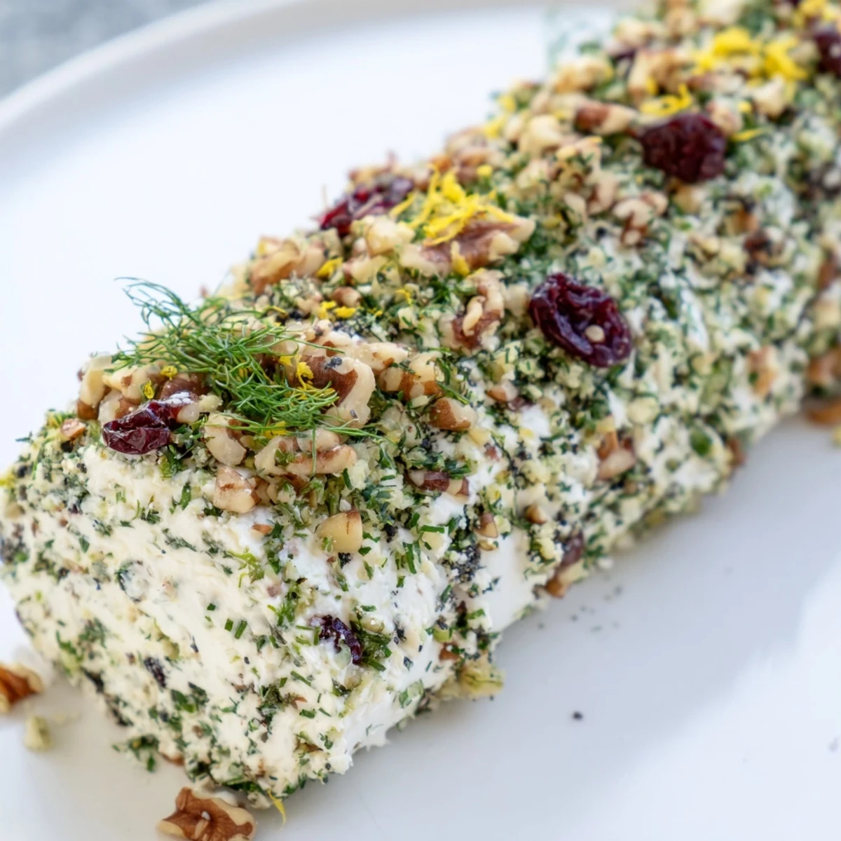 Creamy Winter Snowdrift Goat Cheese Log, richly coated with herbs and cranberries, ready to serve with crackers.
