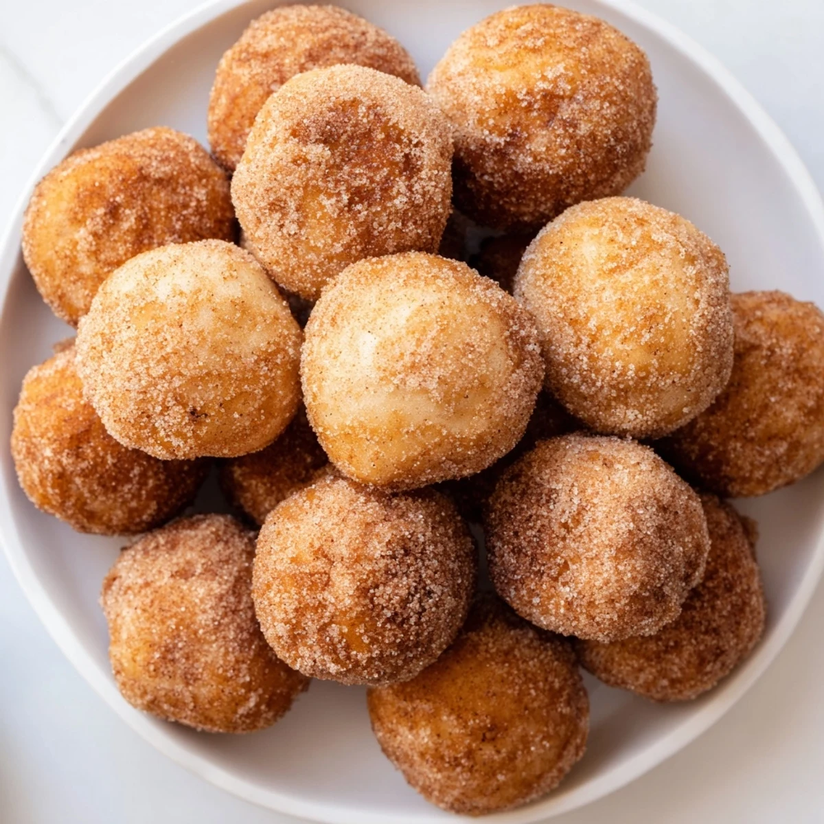 Golden-brown air fryer cinnamon donuts, fresh from the basket, coated in sweet cinnamon sugar.