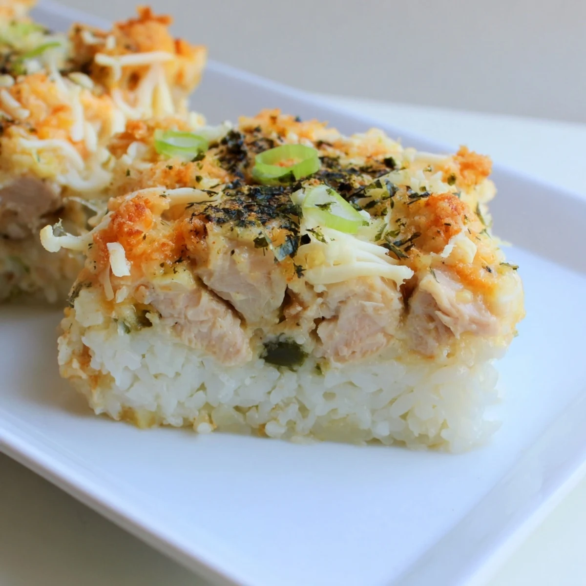 This baked Chicken Sushi Bake features a cheesy, irresistible topping above tender chicken and rice layers.