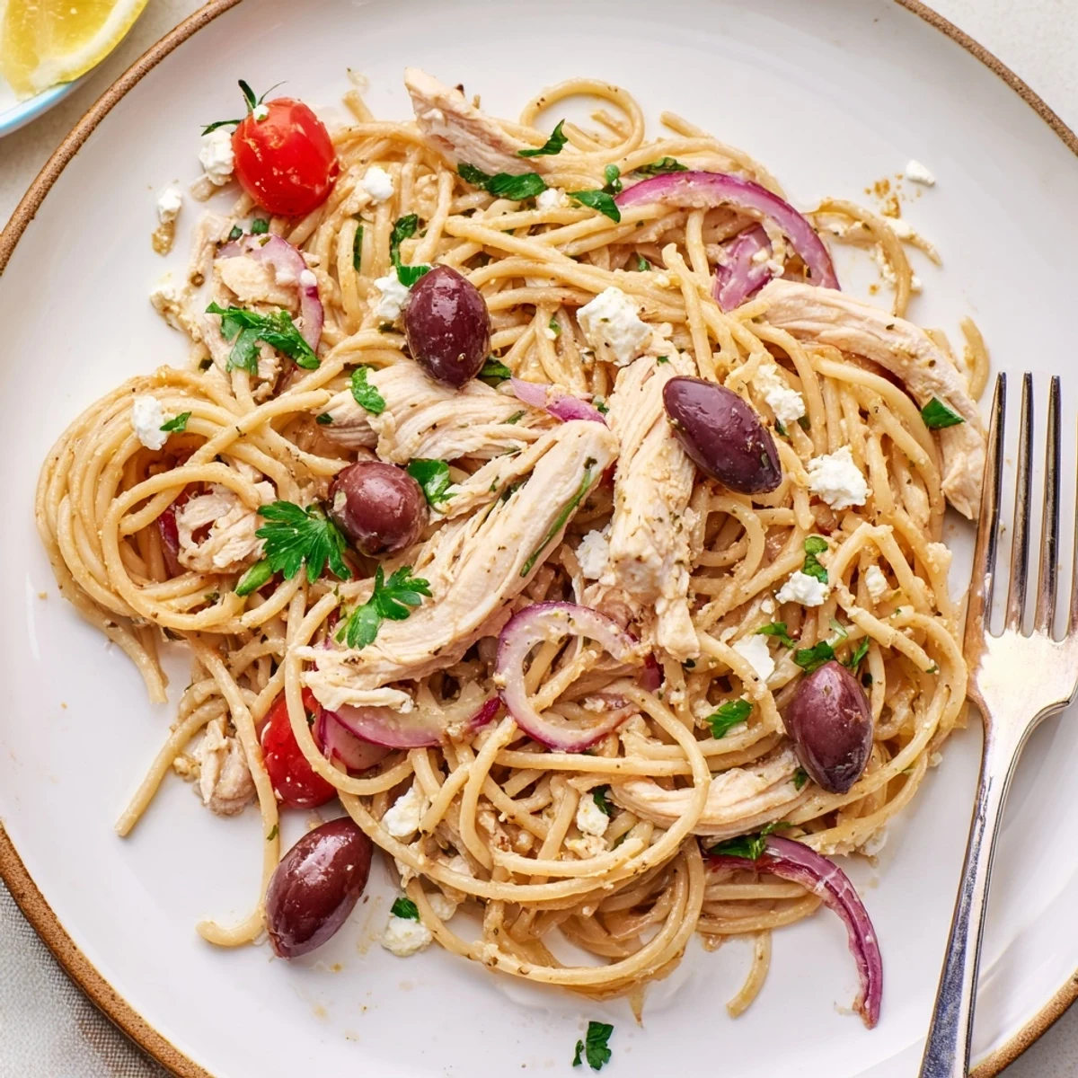 Al dente spaghetti coated in olive oil with juicy chicken, red onion, and colorful tomatoes for an easy Mediterranean dinner.