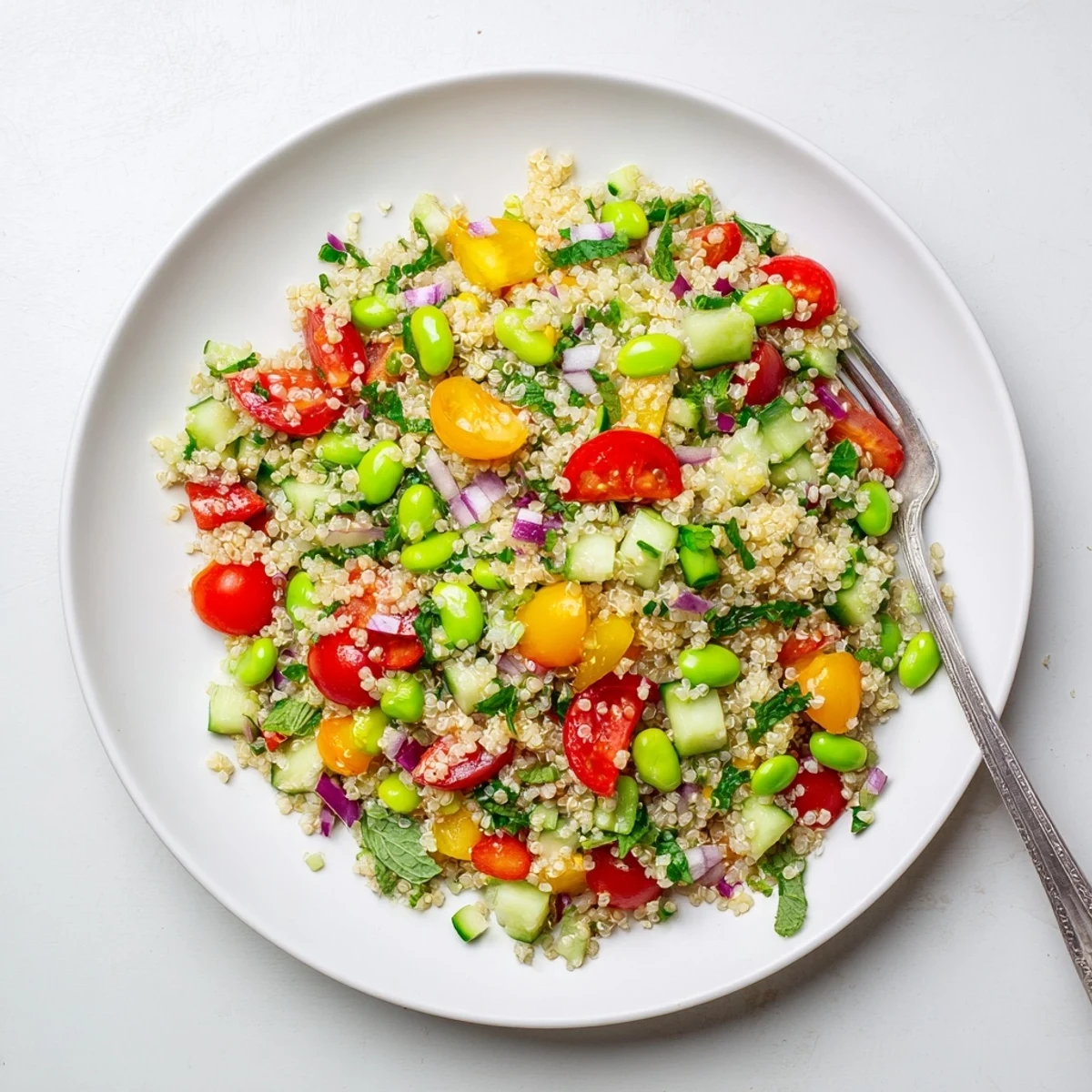 Close-up of Edamame and Quinoa Salad showing diced cucumber and cherry tomatoes tossed in citrus dressing.