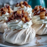 Golden-brown Mini Hot Toddy Pavlovas topped with creamy swirls and spiced, syrupy pears.