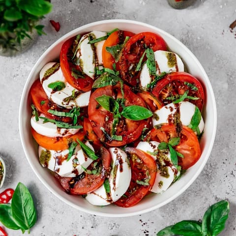 A colorful Caprese salad featuring fresh mozzarella, and a flavorful basil vinaigrette ready to serve.