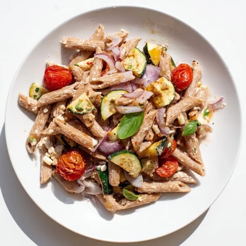 A close-up shot of the baked feta pasta with colorful roasted veggies and bubbling feta cheese.