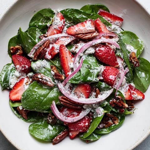 A close-up of a colorful Strawberry Spinach Salad, showing juicy strawberries atop dark spinach.