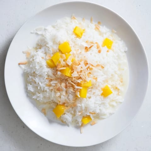 Coconut Rice Sweet simmered in creamy coconut milk, garnished with toasted coconut and tropical fruit for a dessert.