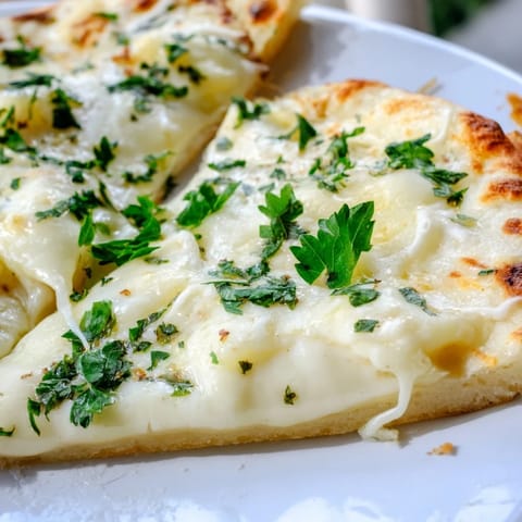 Slices of Creamy Garlic White Pizza showcasing velvety garlic cream sauce and fresh parsley garnish.