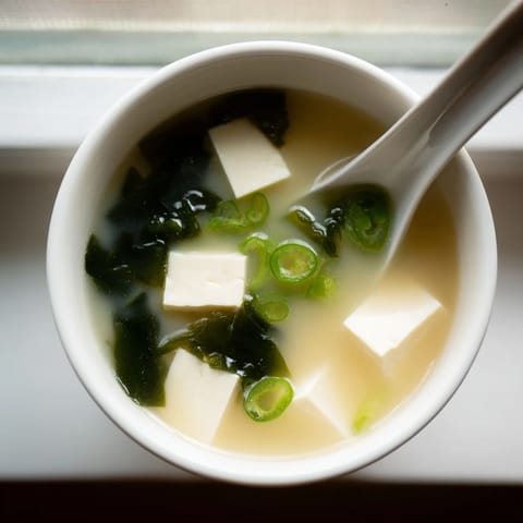 A warm cup of classic miso soup with tofu, featuring tender seaweed and a light savory broth, served as a healthy appetizer.