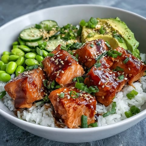 Spicy sriracha mayo drizzles over a colorful Salmon Rice Bowl, creating a vibrant and nutritious meal served fresh.