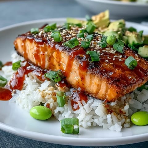Pan-fried Honey Sriracha Salmon glazed in a shiny sauce, served on fluffy jasmine rice with cucumber and edamame.