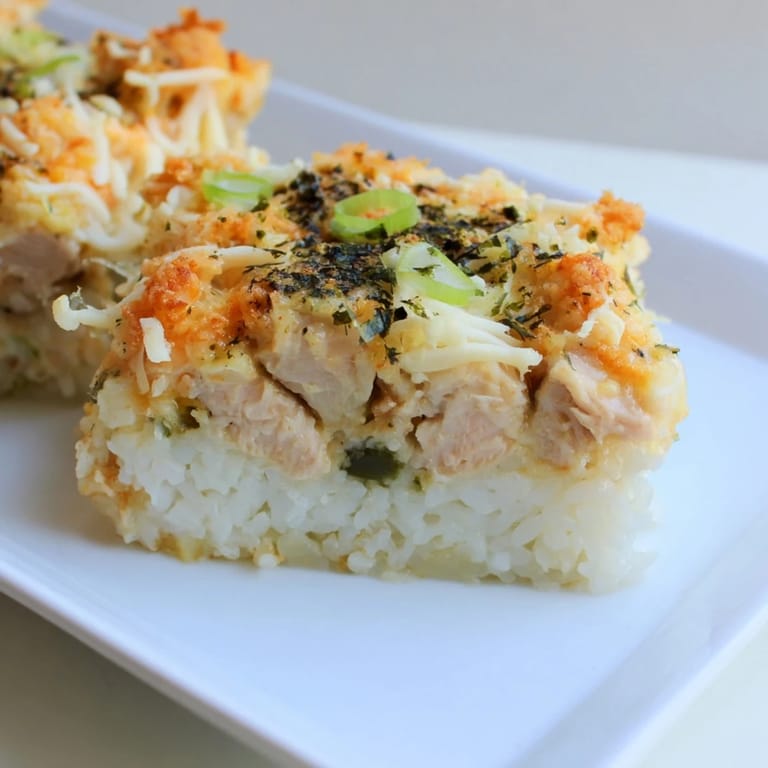 This baked Chicken Sushi Bake features a cheesy, irresistible topping above tender chicken and rice layers.