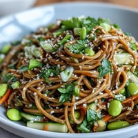 Bright sesame dressing coats chewy Soba Noodle Bowl with crisp cucumbers and bright edamame.
