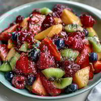 A colorful spring fruit platter with strawberries, kiwi, and pineapple, served with creamy honey-yogurt dipping sauce.