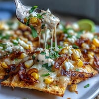 Festive Cinco de Mayo Elote Nachos with creamy chipotle drizzle are a vibrant, cheesy appetizer.